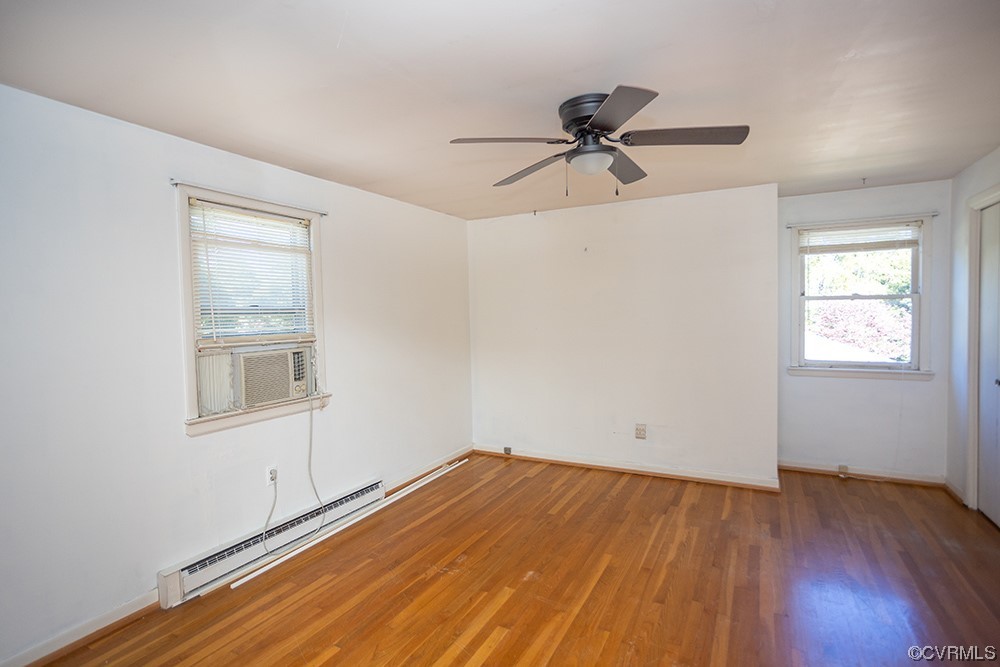 Spare room featuring hardwood / wood-style floors, ceiling fan, and baseboard heating