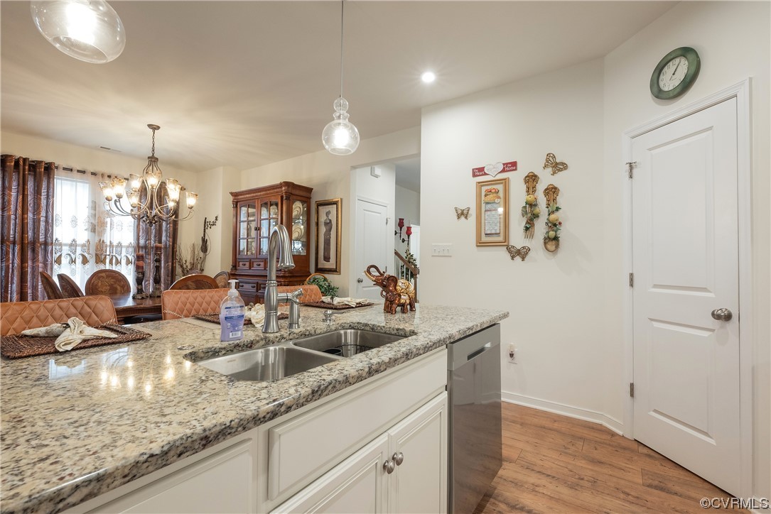 Kitchen featuring hanging light fixtures, dishwasher, light hardwood / wood-style flooring, a notable chandelier, and sink