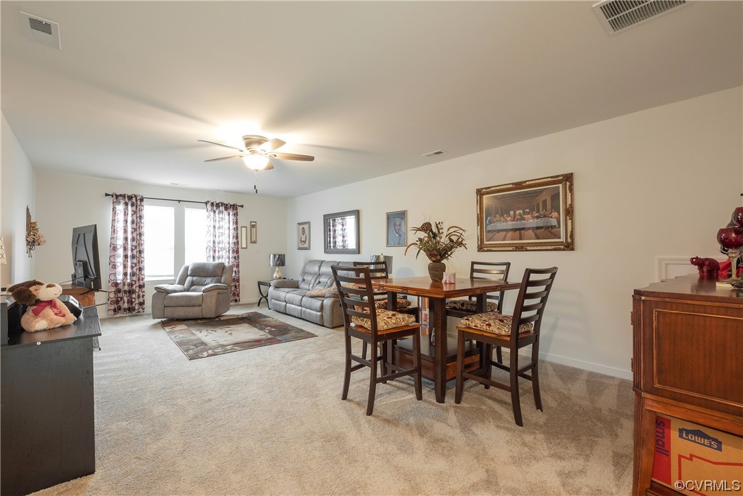 Carpeted dining room featuring ceiling fan