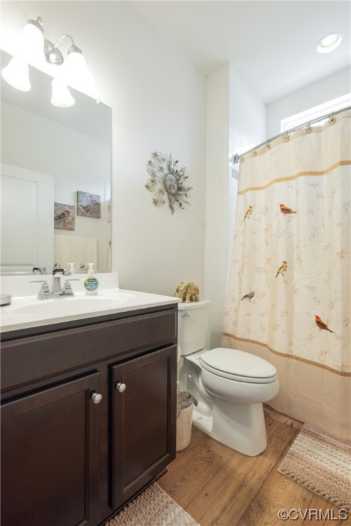 Full bathroom featuring vanity, toilet, shower / bathtub combination with curtain, and hardwood / wood-style floors