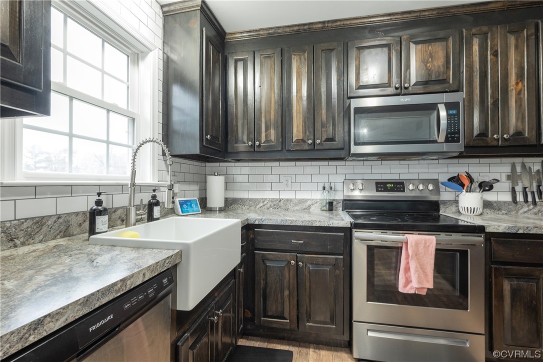 Kitchen with dark brown cabinets, stainless steel appliances, and backsplash
