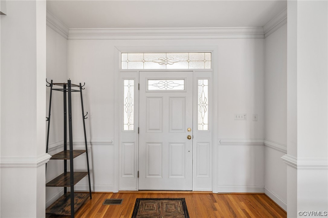 Foyer entrance with ornamental molding and hardwood floors