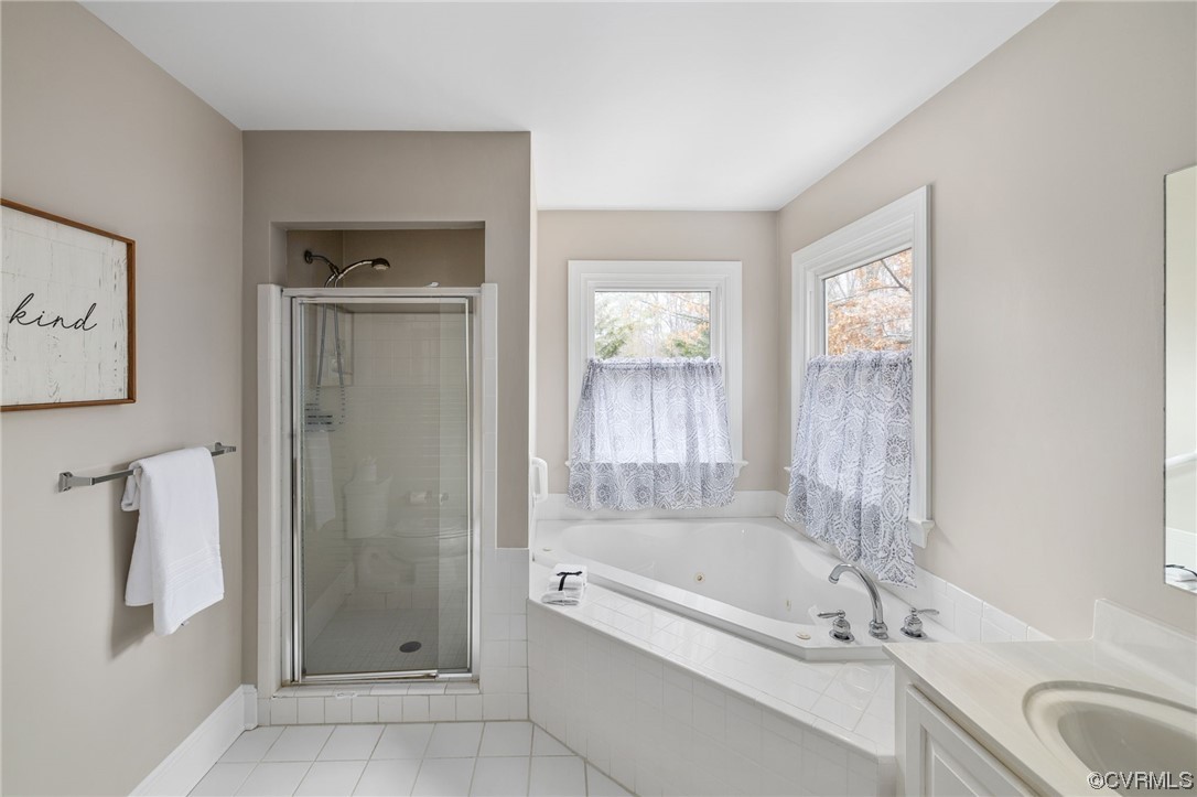 The Primary Bathroom featuring tile floors, vanity, and shower with separate bathtub