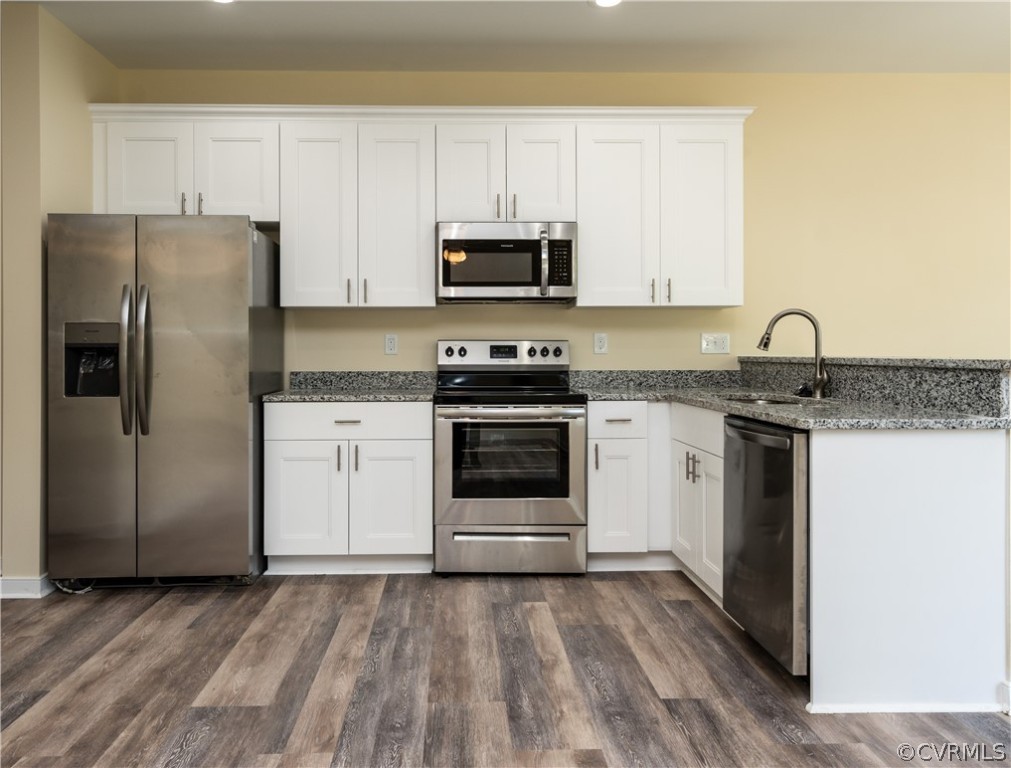 Kitchen featuring white cabinets, appliances with stainless steel finishes, dark hardwood / wood-style floors, and sink