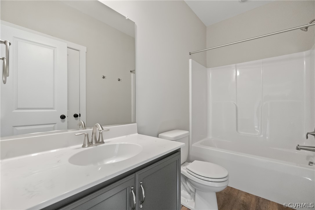 Full bathroom featuring shower / bathtub combination, vanity, toilet, and hardwood / wood-style flooring