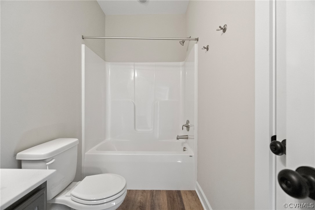 Full bathroom with wood-type flooring, shower / washtub combination, vanity, and toilet