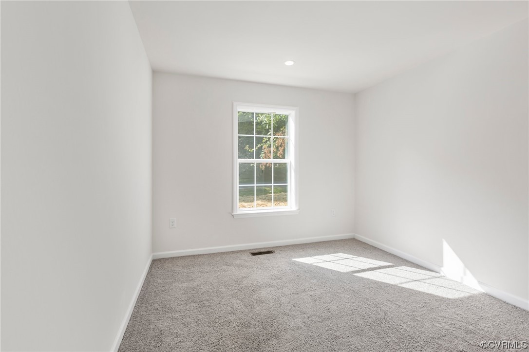 Unfurnished room featuring light carpet and plenty of natural light
