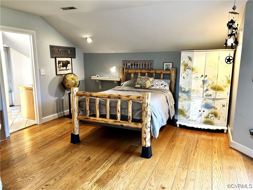 Hardwood floored bedroom featuring lofted ceiling