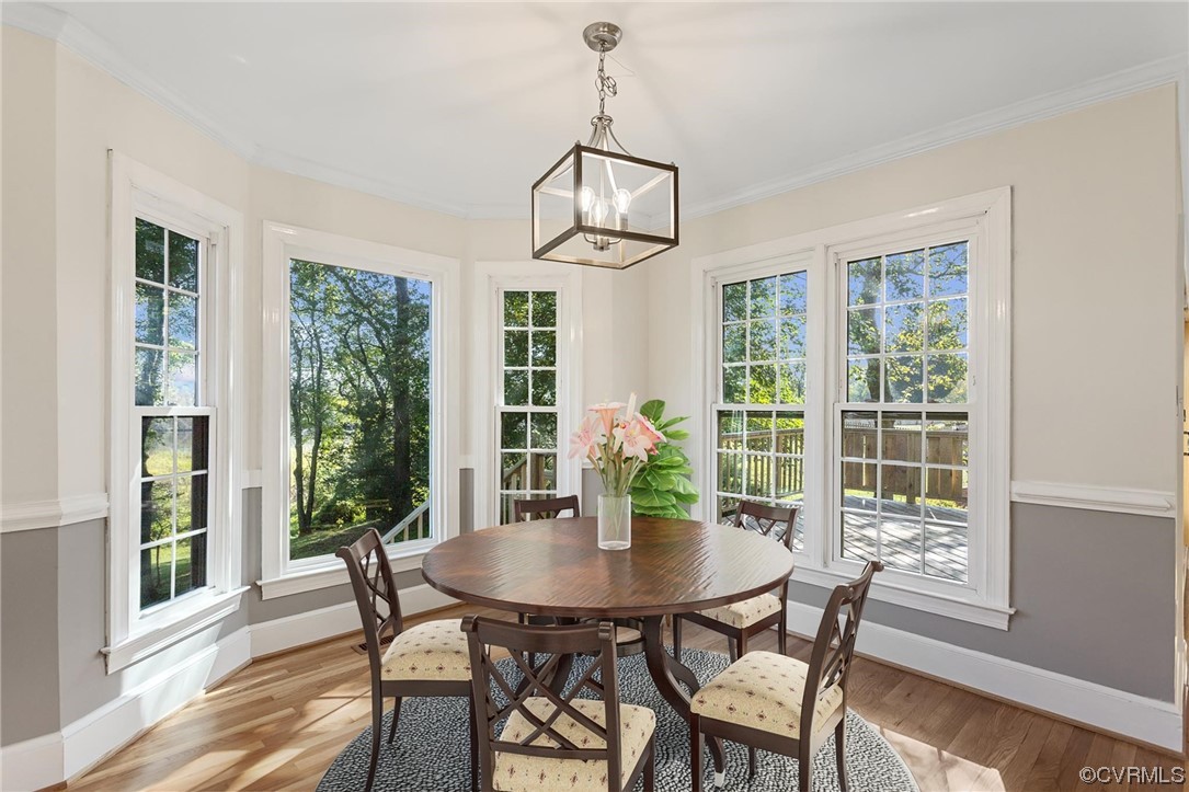 Dining space featuring a notable chandelier, a wealth of natural light, and light hardwood flooring