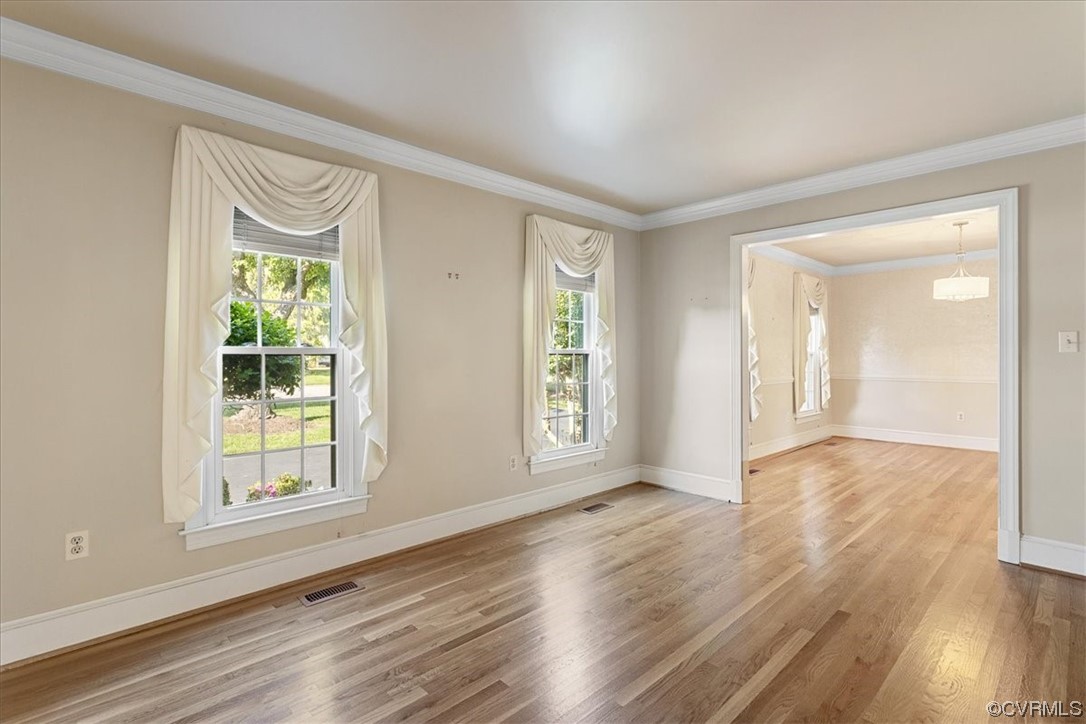 Hardwood floored Living Room with molding, an inviting chandelier, and a wealth of natural light