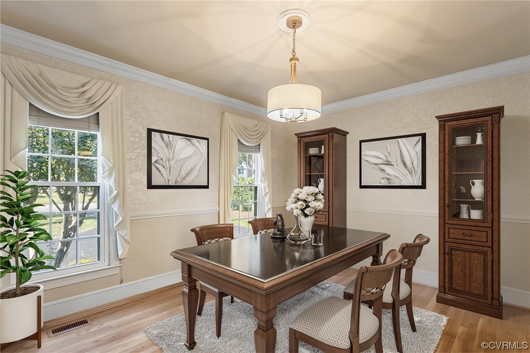 Dining space with crown molding, light hardwood floors, and plenty of natural light
