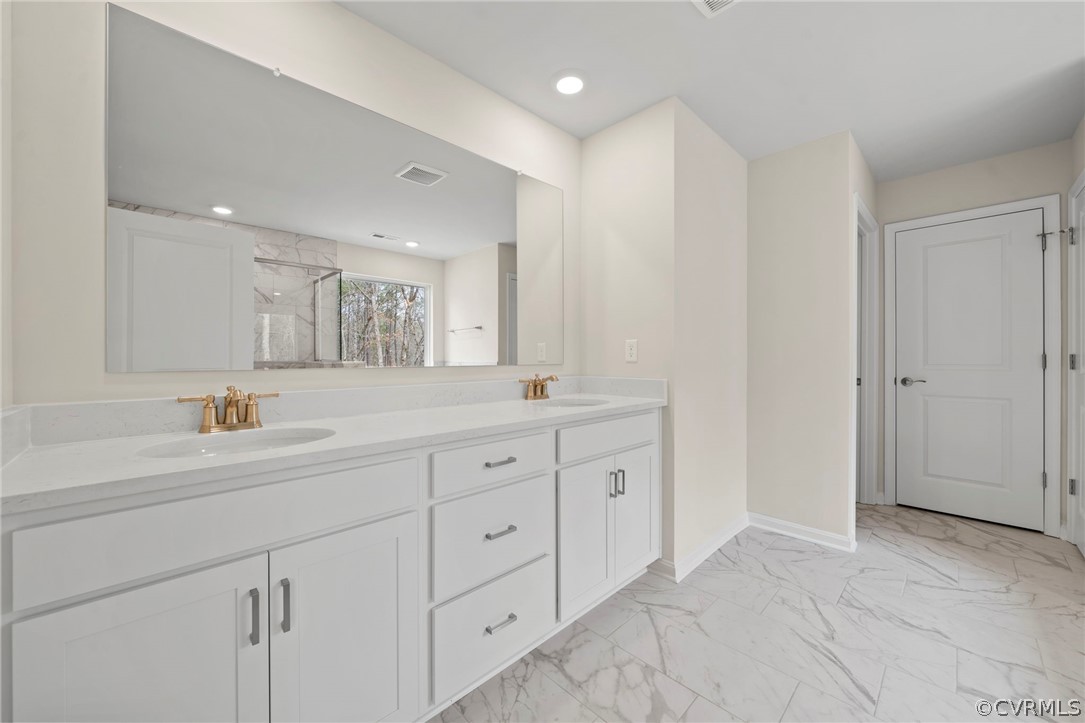 Bathroom with walk in shower, dual sinks, vanity with extensive cabinet space, and tile floors