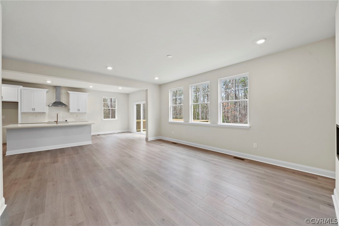 Unfurnished living room featuring sink and light hardwood / wood-style floors