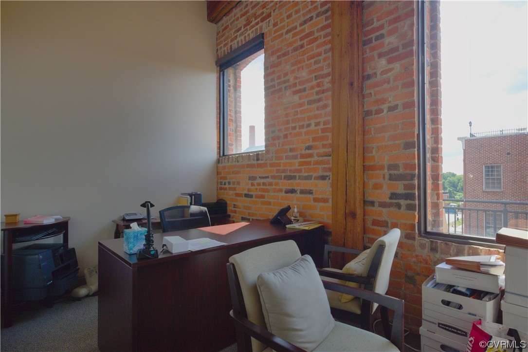 Office space featuring brick wall and dark carpet