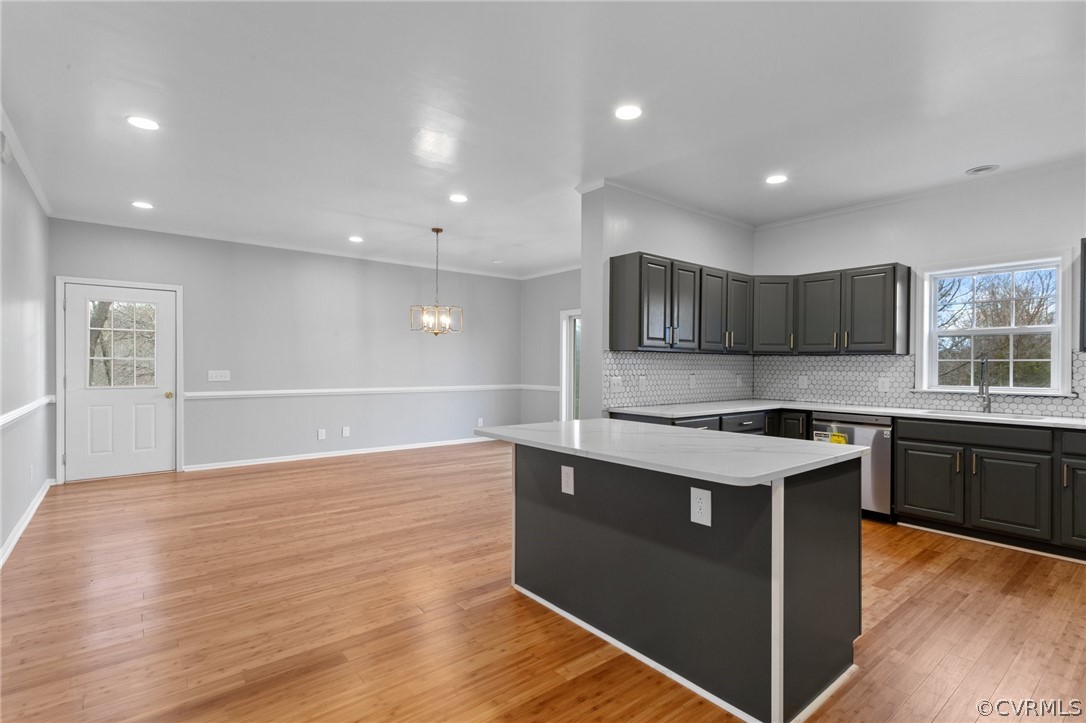 Kitchen with gray cabinetry, backsplash, light hardwood / wood-style flooring, and dishwasher