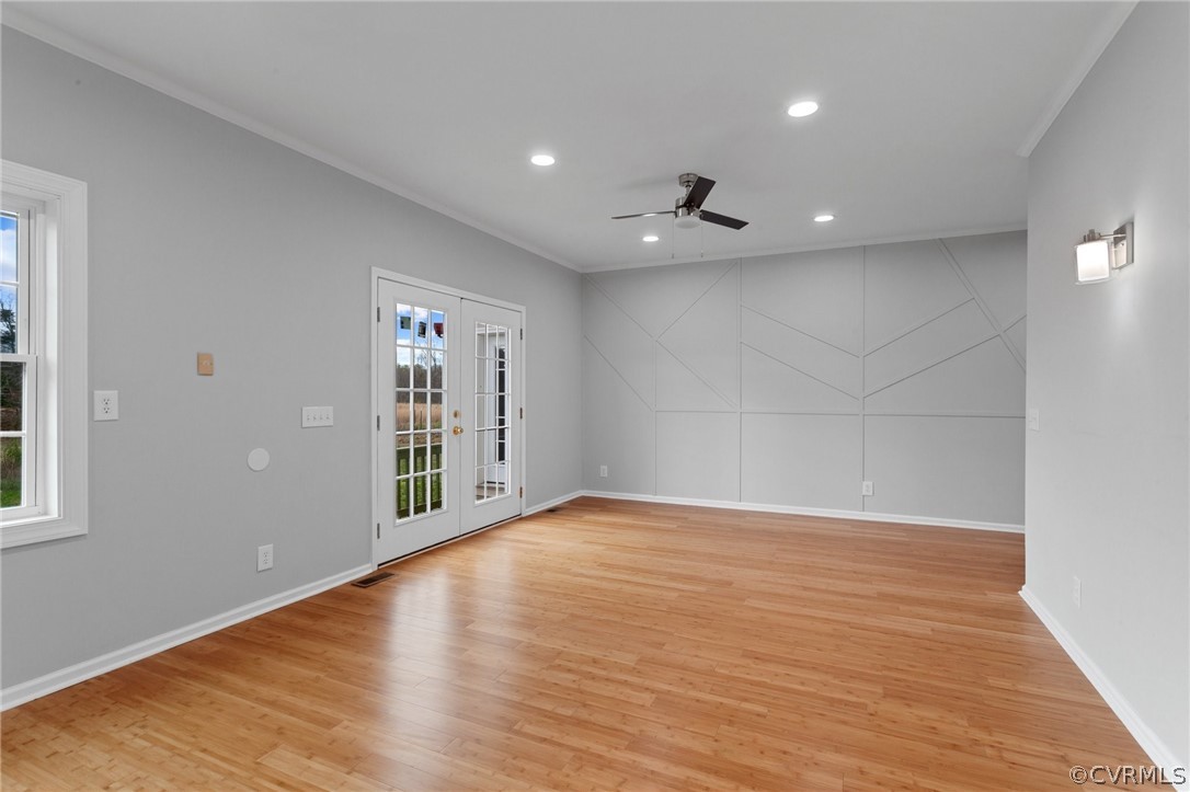 Empty room featuring crown molding, french doors, ceiling fan, and light wood-type flooring