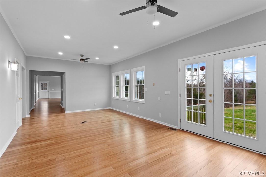 Empty room with ceiling fan, light hardwood / wood-style flooring, and plenty of natural light