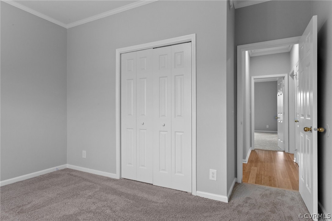 Unfurnished bedroom with crown molding, a closet, and light wood-type flooring
