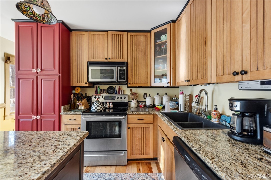 Kitchen featuring light hardwood / wood-style flooring, sink, light stone countertops, and stainless steel appliances