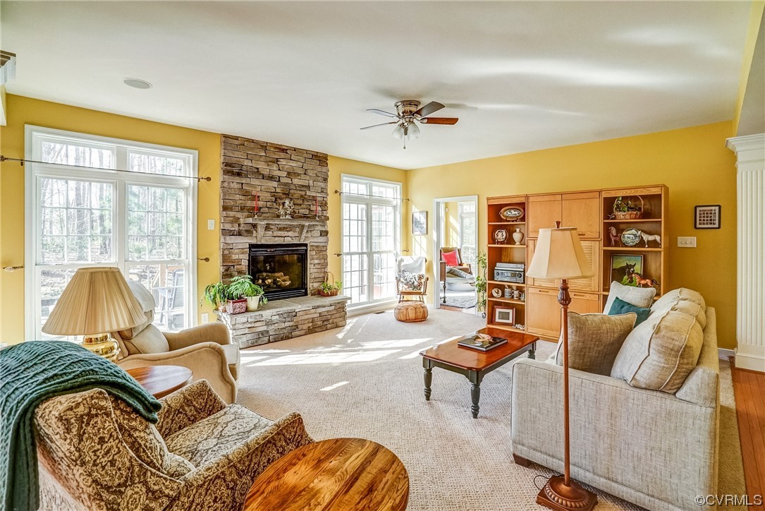 Carpeted living room with a fireplace, a wealth of natural light, and ceiling fan