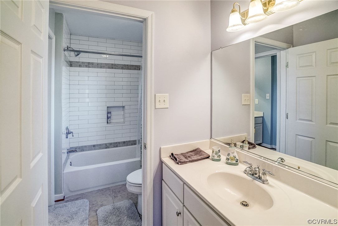 Full bathroom with vanity, toilet, tiled shower / bath, and tile flooring