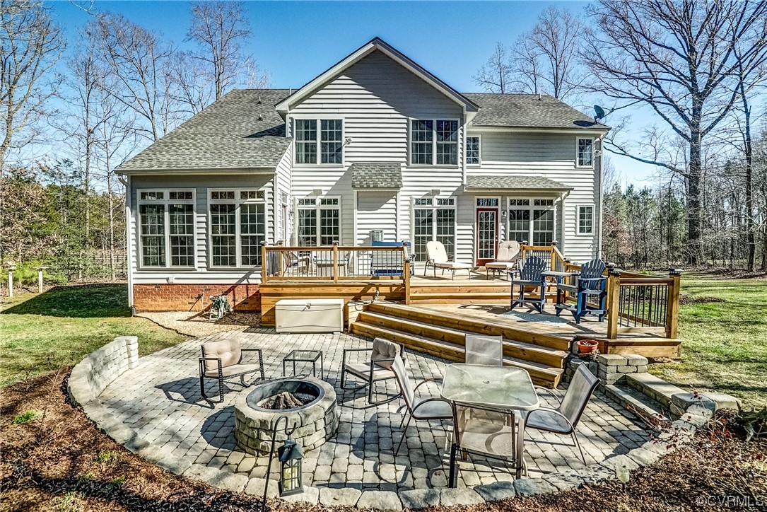 Back of property featuring a deck, a patio, and a fire pit
