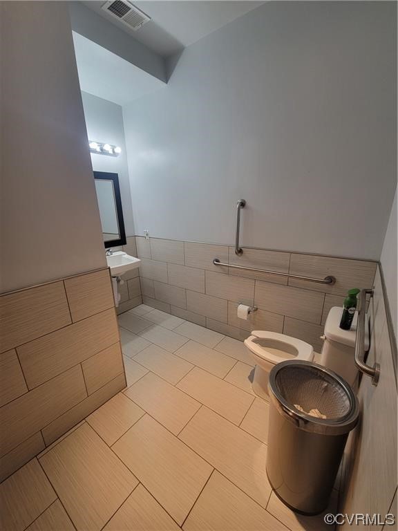 Bathroom featuring vanity, toilet, tile walls, and tile flooring