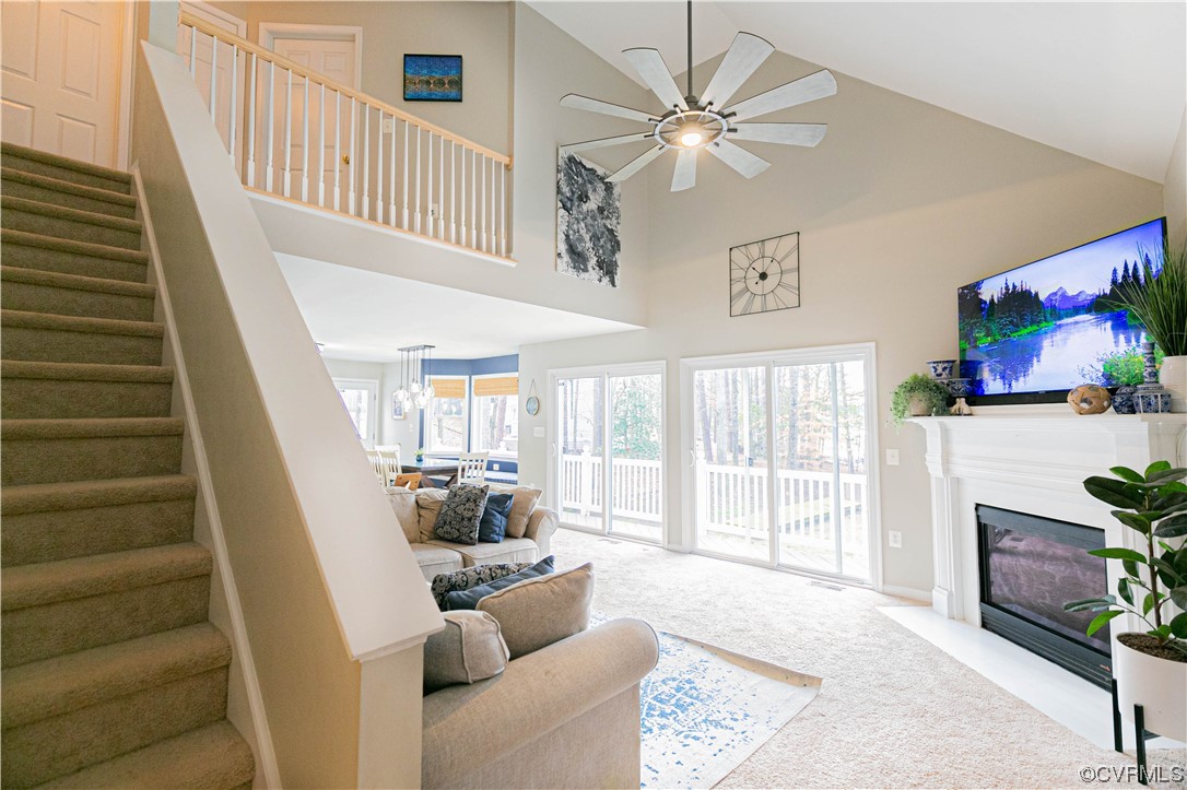 Carpeted living room featuring ceiling fan and a high ceiling