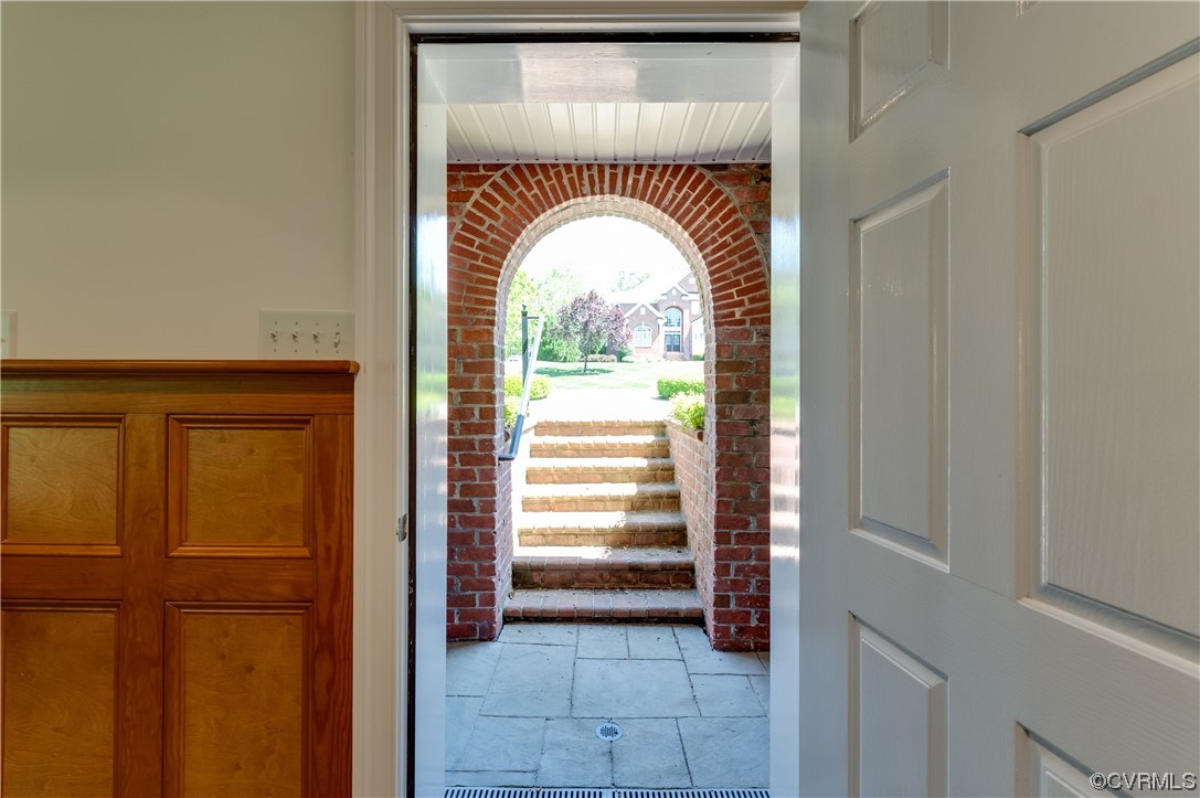 Doorway with brick wall and light tile flooring