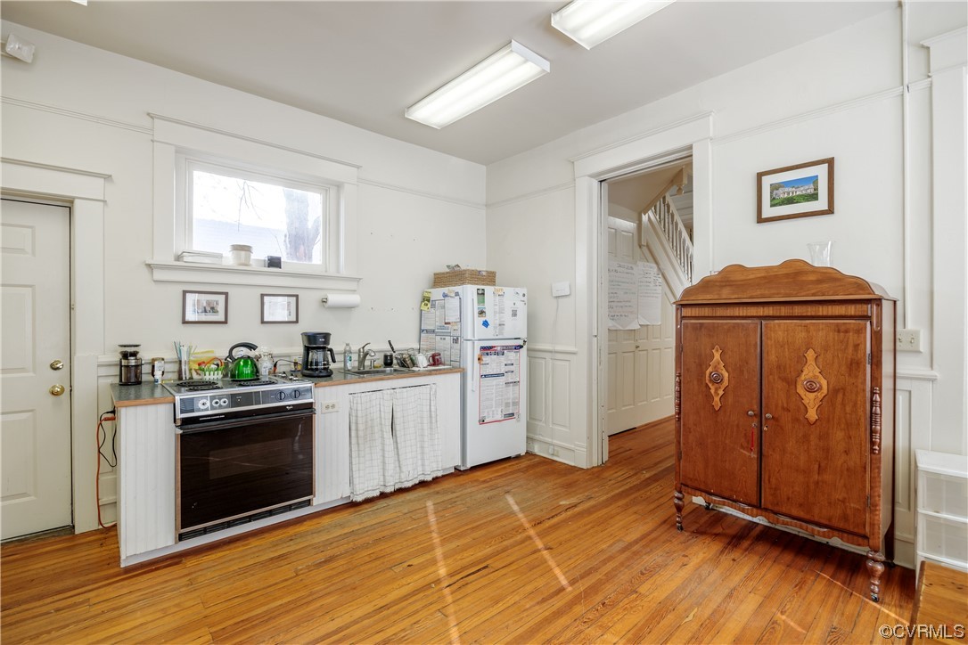 Kitchen with white fridge, light hardwood / wood-style flooring, electric stove, and sink