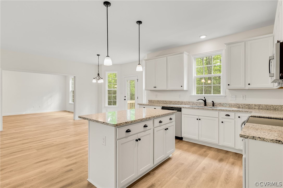 Kitchen featuring white cabinets, pendant lighting, light wood-type flooring, and stainless steel appliances