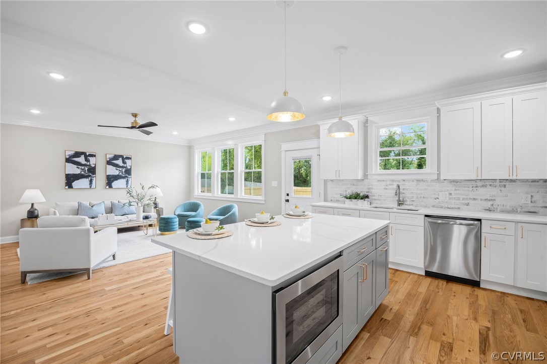 Kitchen featuring a center island, stainless steel appliances, light hardwood / wood-style floors, and decorative light fixtures