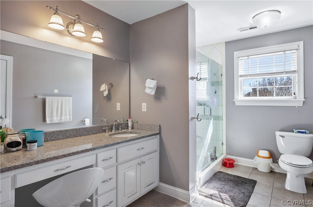 Bathroom featuring vanity, toilet, tile flooring, and walk in shower