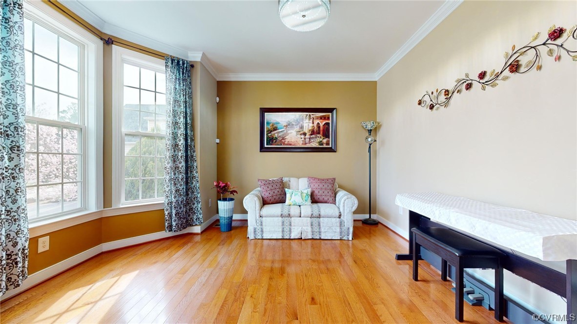 Living area with plenty of natural light, ornamental molding, and light hardwood wood floors