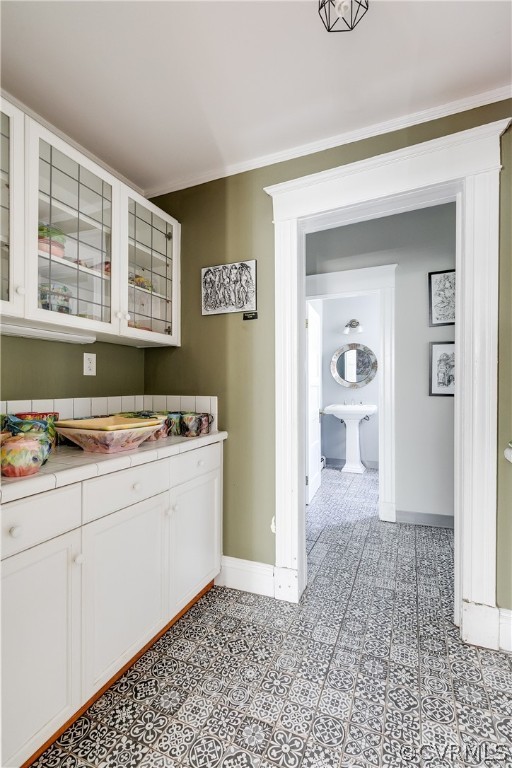 Butler's Pantry with cabinetry, ornamental molding, and light tile floors