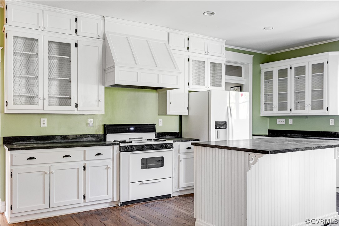 Kitchen featuring white appliances, dark hardwood / wood-style floors, custom range hood, a center island, and white cabinetry