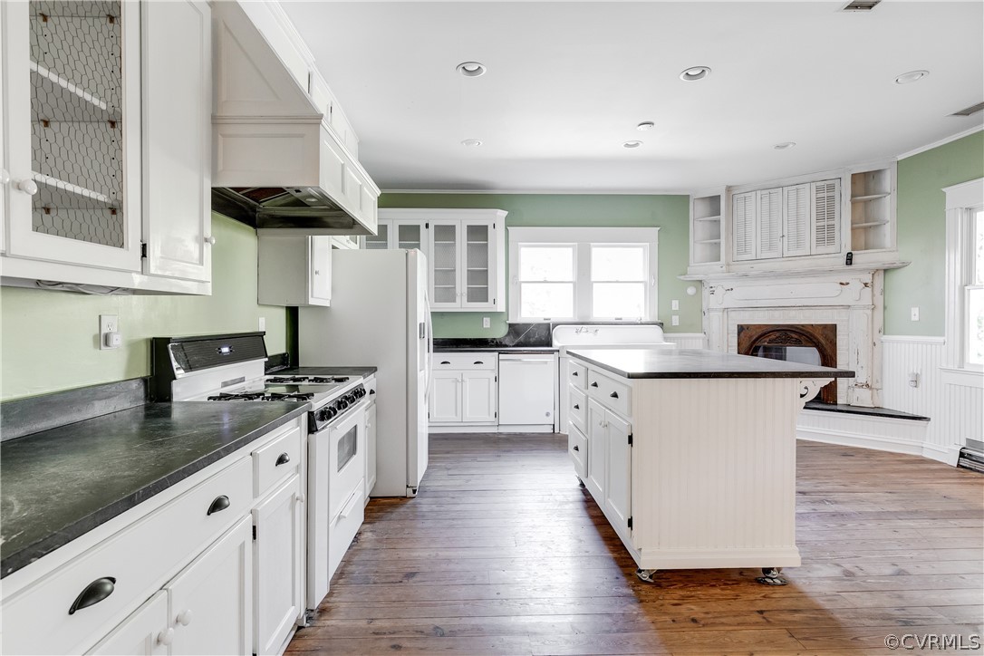 Kitchen with white cabinets, dark hardwood / wood-style flooring, white appliances, and custom range hood
