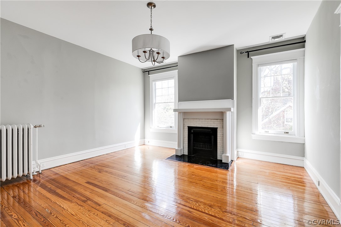 Third Bedroom with a notable chandelier, light hardwood / wood-style floors, a wealth of natural light, and radiator