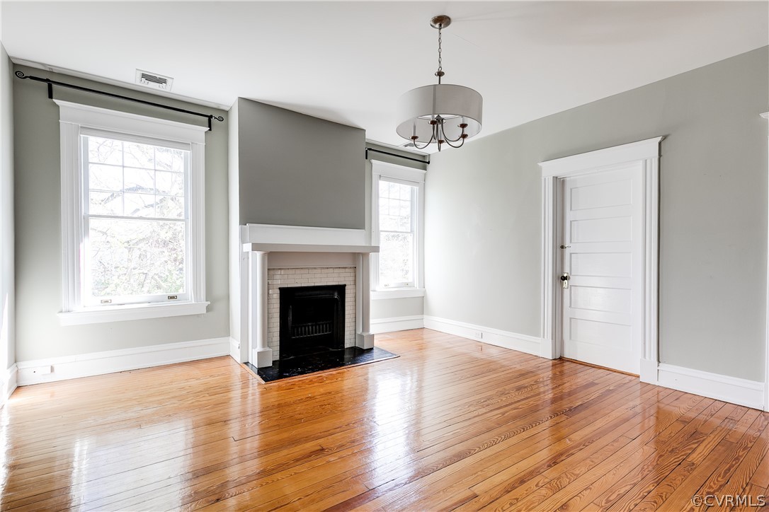 Third Bedroom with a fireplace, a notable chandelier, and light hardwood / wood-style floors