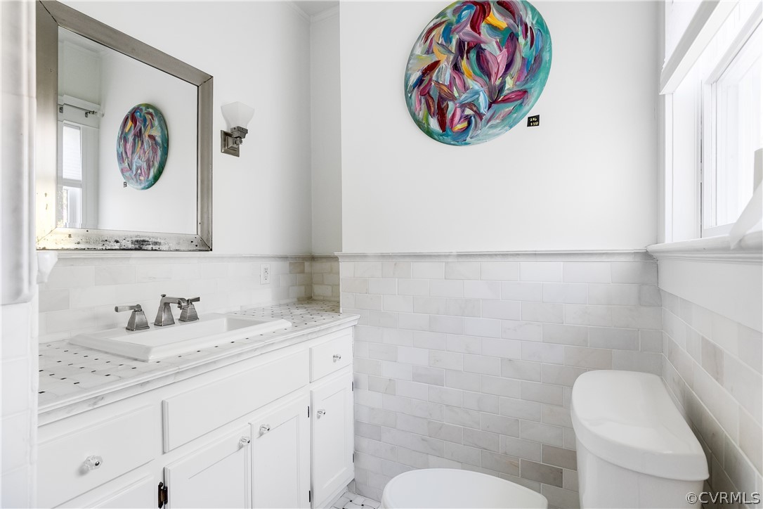 En-Suite Bathroom with tile walls, tasteful backsplash, vanity, and toilet