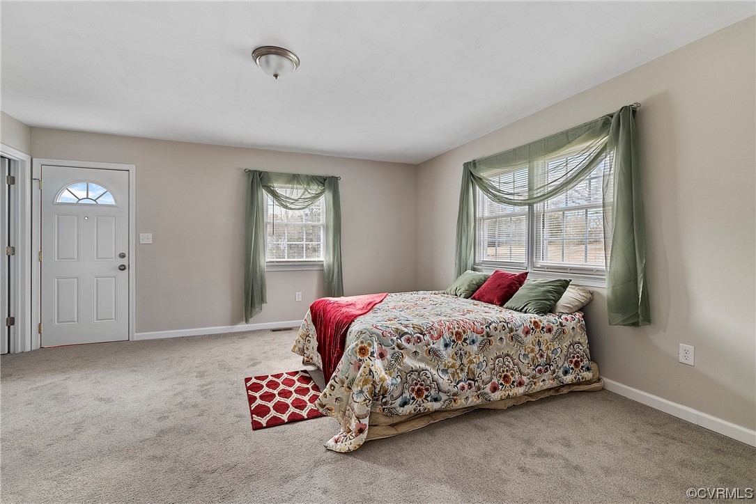 Carpeted bedroom with multiple windows, master bathroom, and walk in closet