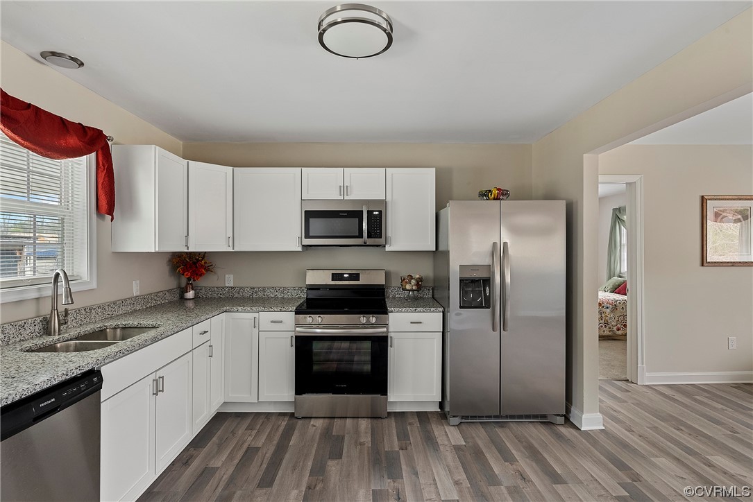 Kitchen featuring sink, white cabinets, stainless steel appliances, and LPV flooring