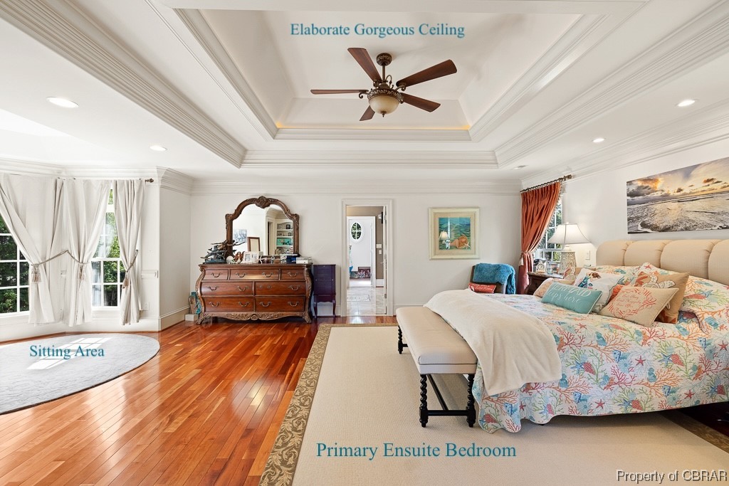 Bedroom featuring dark wood-type flooring, a raised ceiling, ornamental molding, and ceiling fan