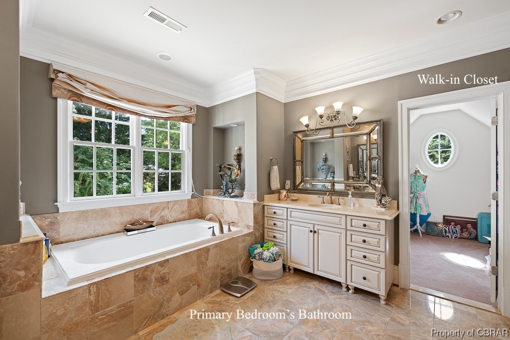 Bathroom featuring oversized vanity, tile floors, ornamental molding, and a relaxing tiled bath