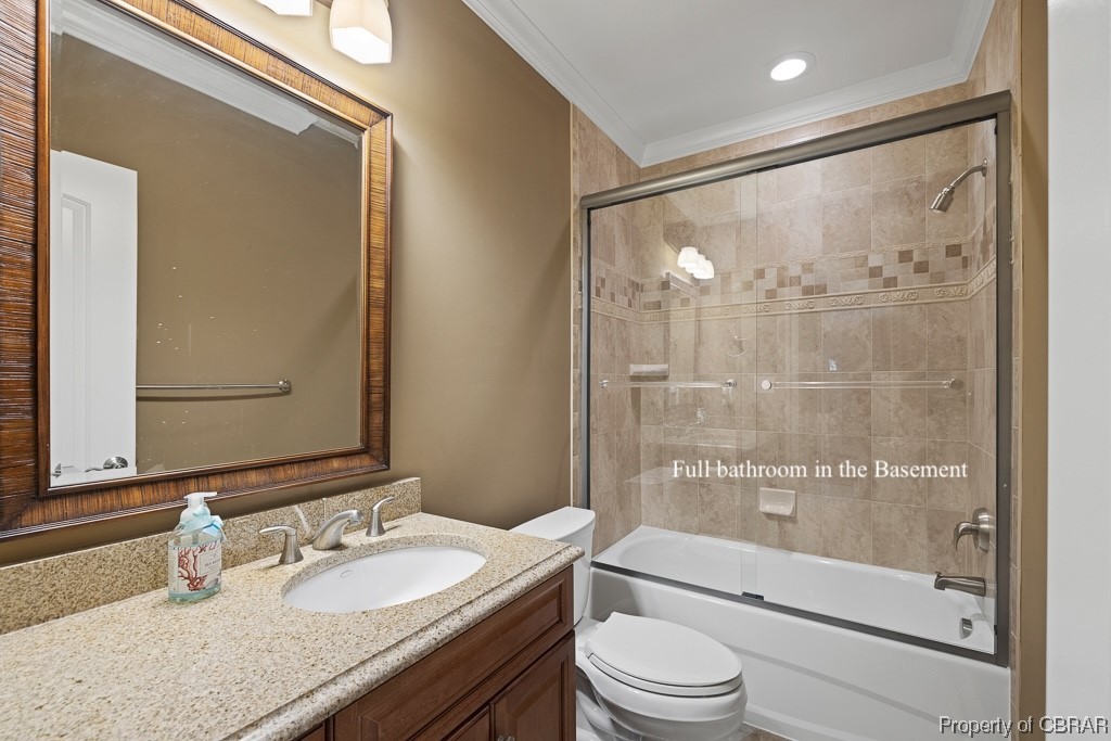 Full bathroom with combined bath / shower with glass door, vanity, crown molding, and toilet