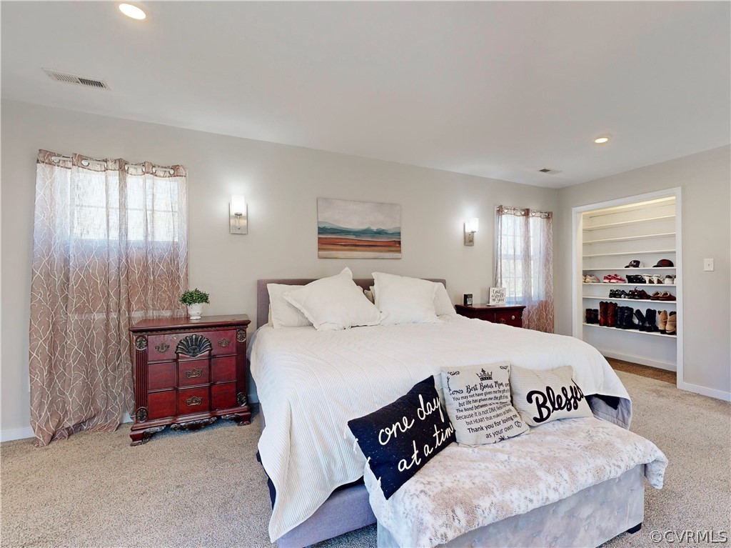 Bedroom featuring a spacious closet, light colored carpet, a closet, and ceiling fan