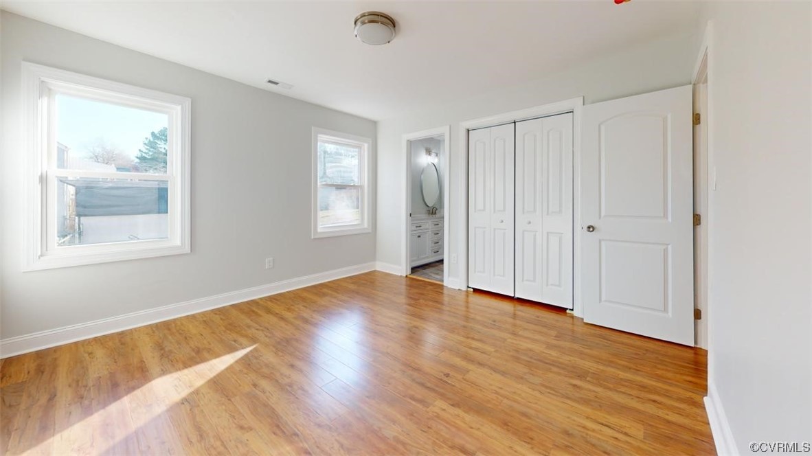 Primary bedroom featuring ensuite bath, light hardwood / wood-style floors, and a closet