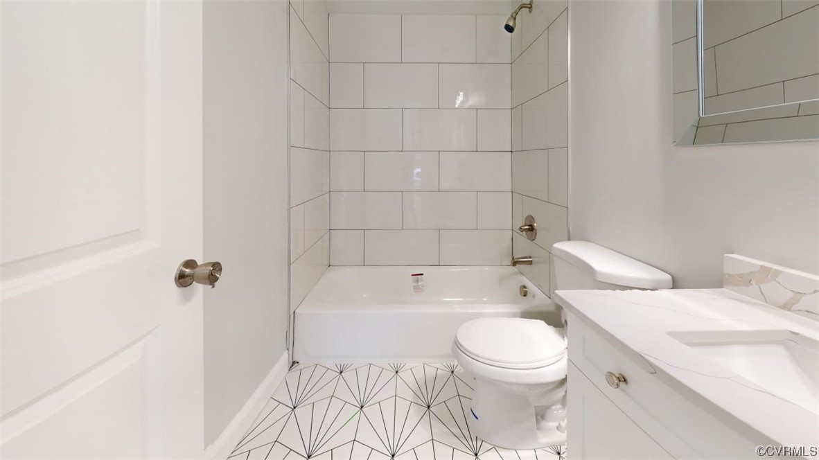 Full bathroom featuring tile flooring, large vanity, tiled shower / bath, and toilet