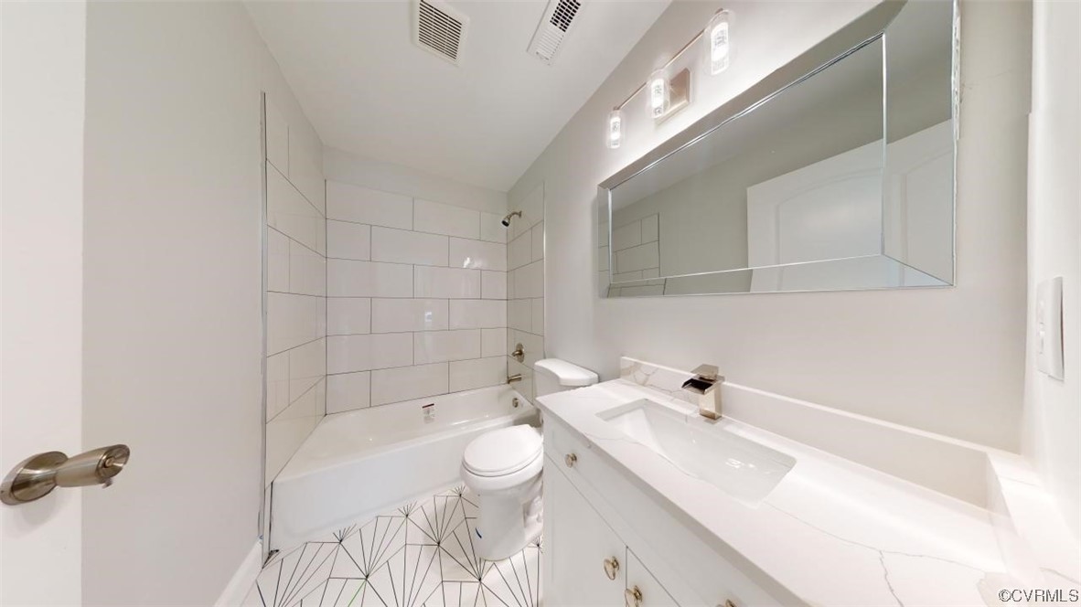 Full bathroom featuring toilet, tiled shower / bath, large vanity, and tile floors