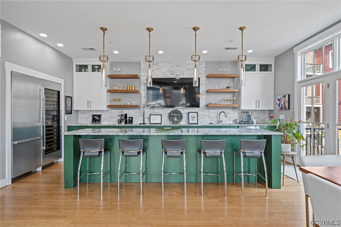 Entertaining Kitchen with hanging light fixtures, light hardwood / wood-style flooring, white cabinets, and backsplash